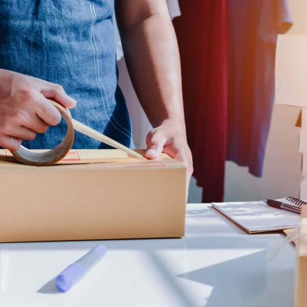 Closeup view of man online store small business owner seller entrepreneur packing package post shipping box preparing delivery parcel on table. entrepreneurial self employed business concept.
